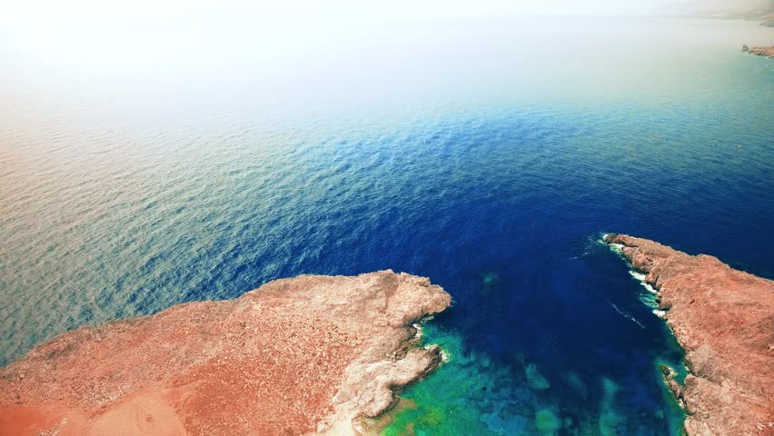 Blue sea, waves breaking in cliffs at shore