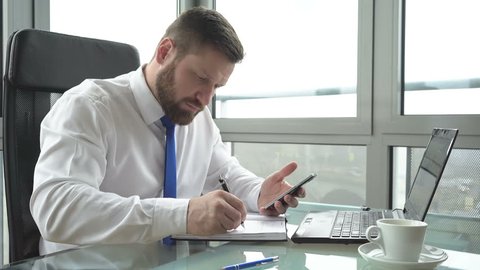 Businessman making notes from smartphone Slider and pan shot
