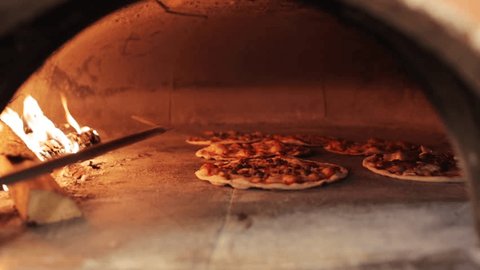 food, italian kitchen and cooking concept - peel placing pizza baking in oven at pizzeria
