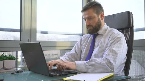 Businessman working, writing on laptop computer in office
