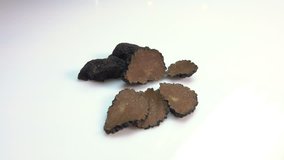 Camera approaching slices of black truffle on a white surface