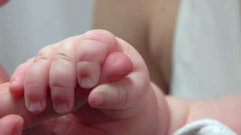 Baby holding an adult's hand with tiny fingers