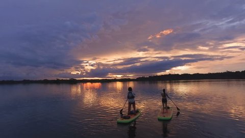 Aerial - A group doing SUP yoga on paddleboards in a star shape with sky reflection - Amazon, Ecuador