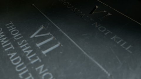 A slow close up pan across a stone tablet with the first five of the ten commandments inscribed onto them