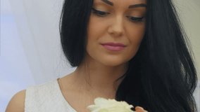 Young pretty woman smelling white rose flower and dreaming