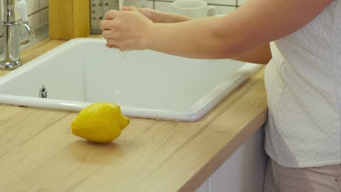 Female hands washing orange in the water