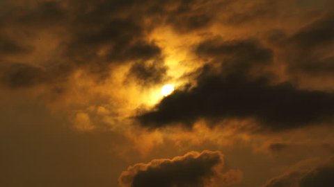 Cloudscape with sun shining behind dark storm clouds
