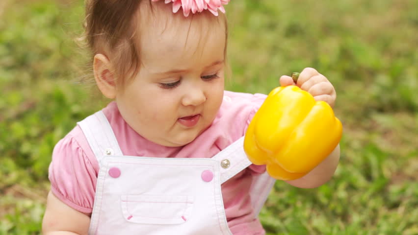 Baby girl eating pepper outdoor