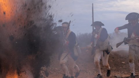 VIRGINIA - OCTOBER 2014 - Reenactment, large-scale, epic American Revolutionary War anniversary recreation - in the midst of battle.  British Redcoats fire on charging Continental Soldiers. Explosions