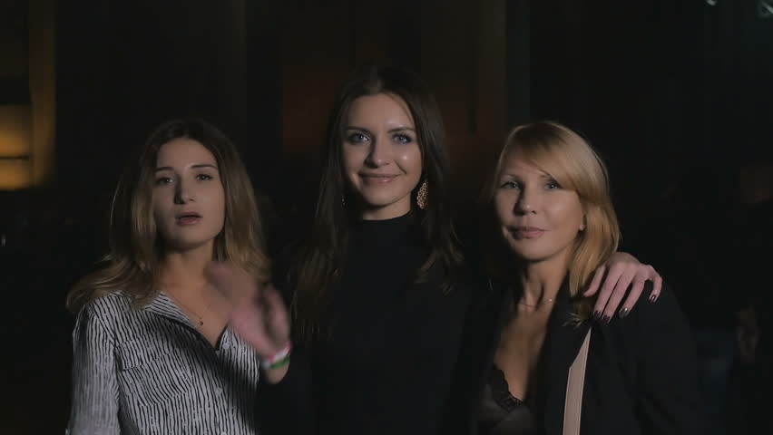 Three smiling women waving hands and send a kiss to the camera