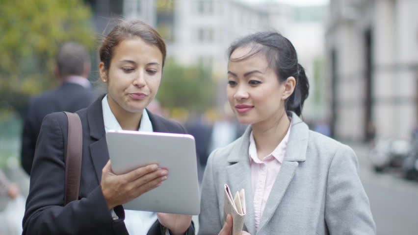4K Portrait smiling businesswomen using computer tablet outdoors in the city
