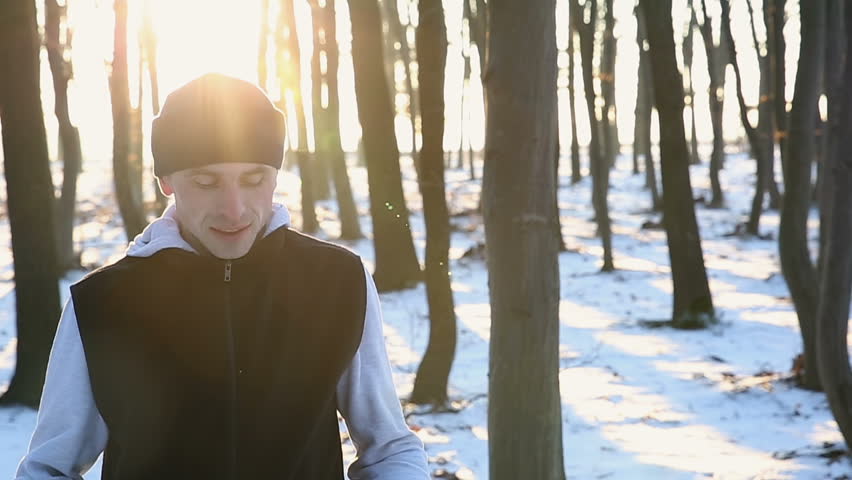 Young runner with headphones in the park at sunset. Winter training for recuperation
