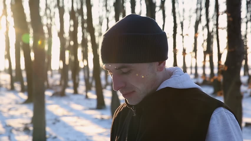 Sports guy with headphones in the park at sunset