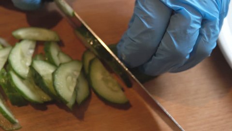 Cucumber cutting. Preparation of salad from fresh vegetables of cucumbers, tomato and onions shallot