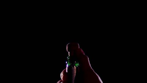 Champagne bottle is opened and sprinkled. Slow motion, black background