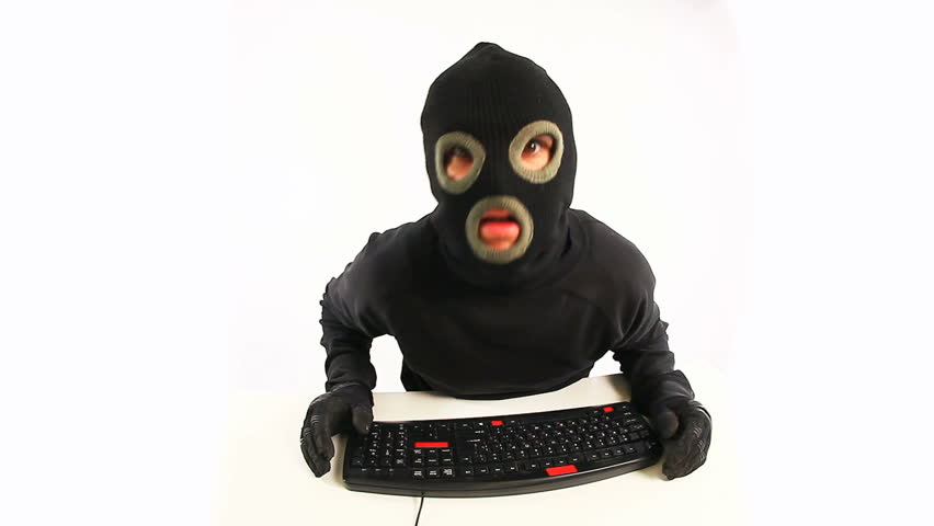 Guy in balaclava typing something on the keyboard