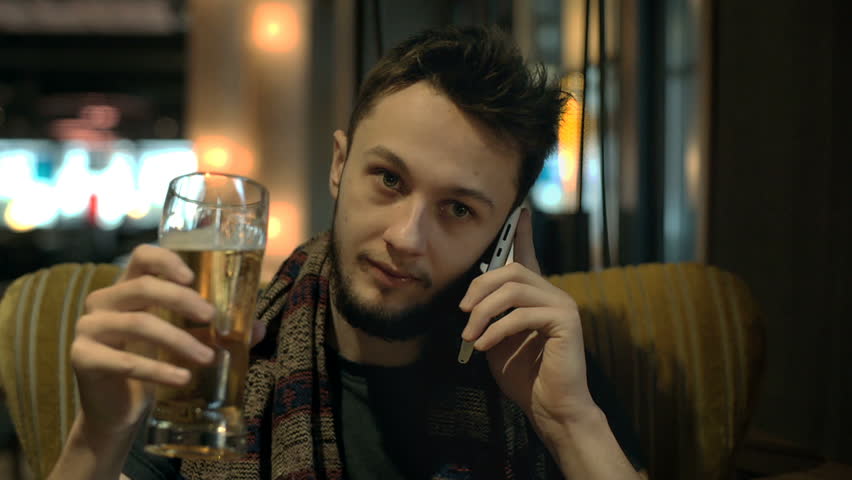 Happy man sitting in the pub with a beer and chatting on cellphone
 | Shutterstock HD Video #24898907