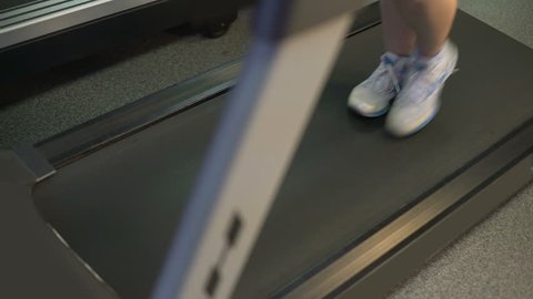 Young woman with excess weight actively exercising on treadmill for weightloss