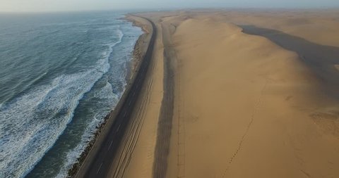 4K aerial drone view of Namibian Atlantic coastline, road along the coast from Swakopmund to Walvis Bay,  beach, surf break point, landscape with ocean background of sand dunes at Namibia's west coast