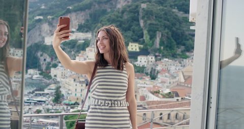 Tourist woman having video chat showing view sharing authentic travel experience from hotel balcony at sunset using smart phone connecting with friends on social media summer vacation in Amalfi Italy