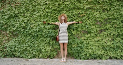 Tourist woman posing in front green wall of plants vertical garden girls enjoying European summer holiday travel vacation adventure