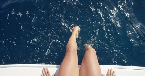 Top view female legs in water Woman splashing and playing with feet in ocean off edge of baot enjoying European summer holiday travel vacation adventure in Amalfi Coast Italy from above