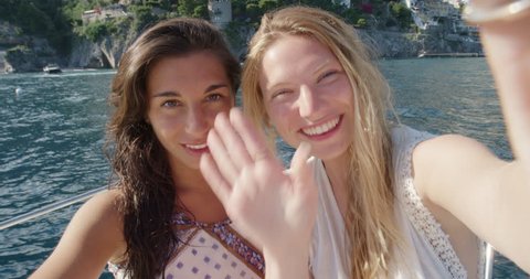 Best friends having video chat on holiday Happy women on boat waving at family on mobile phone camera sharing European summer travel vacation adventure in Positano Amalfi Coast Italy