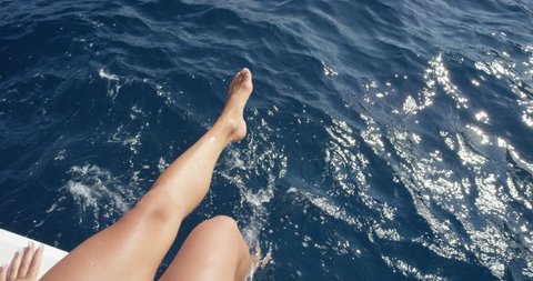 Top view female legs in water Woman splashing and playing with feet in ocean off edge of boat enjoying European summer holiday travel vacation adventure in Amalfi Coast Italy from above