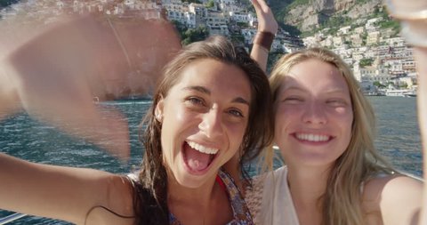 Best friends having video chat on holiday Happy women on boat waving at family on mobile phone camera sharing European summer travel vacation adventure in Positano Amalfi Coast Italy