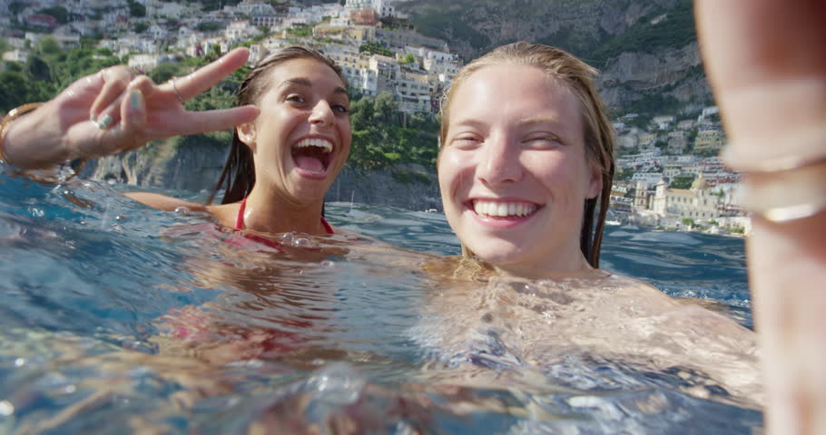 Girl friends taking selfie photograph in water with Positano town in background Tourist women enjoying European summer holiday travel vacation adventure in Amalfi Coast Italy | Shutterstock HD Video #24912935