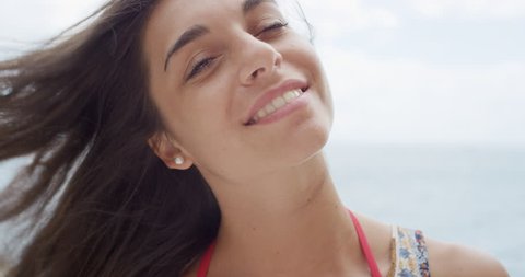 Close up portrait of Beautiful Young Woman smiling hair blowing in wind on tropical beach slow motion