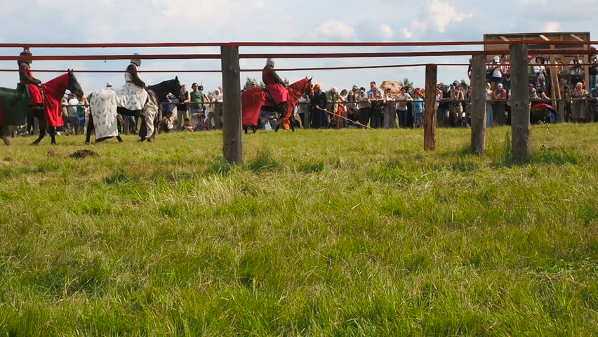 Knights on horseback goes through the green field . Festival of the European Middle Ages. Medieval joust with knights on a hors in armour and costume.