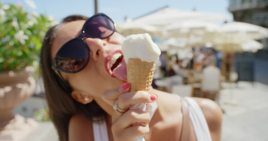 Young woman eating ice cream on beach Girl licking Italian Gelato outdoors ...