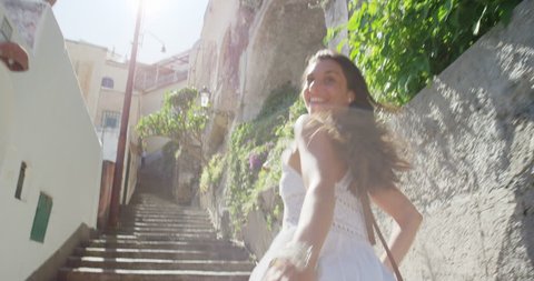 Happy Young Tourist Woman running up through street in Italian town smiling and laughing POV travel concept Amalfi Coast Positano Italy Rear view