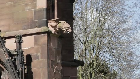 An Ugly Gothic Gargoyle Dragon looms from the stone walls of Lichfield Cathedral, hand carved and impressive, an architectural treat for the eyes.