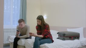 Couple sitting on the bed, not talking to each other after quarrel, typing on smartphones
