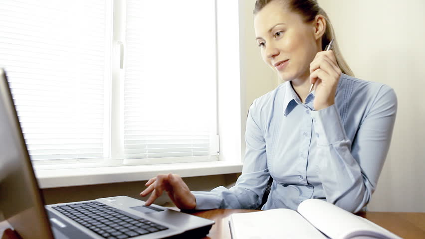 Businesswoman sitting on the desk and working with laptop