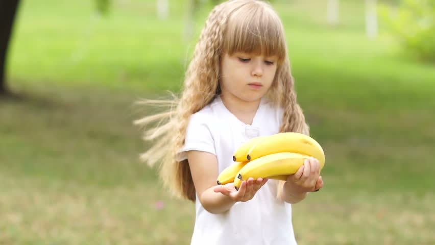 Girl shows the viewer a bunch of bananas
