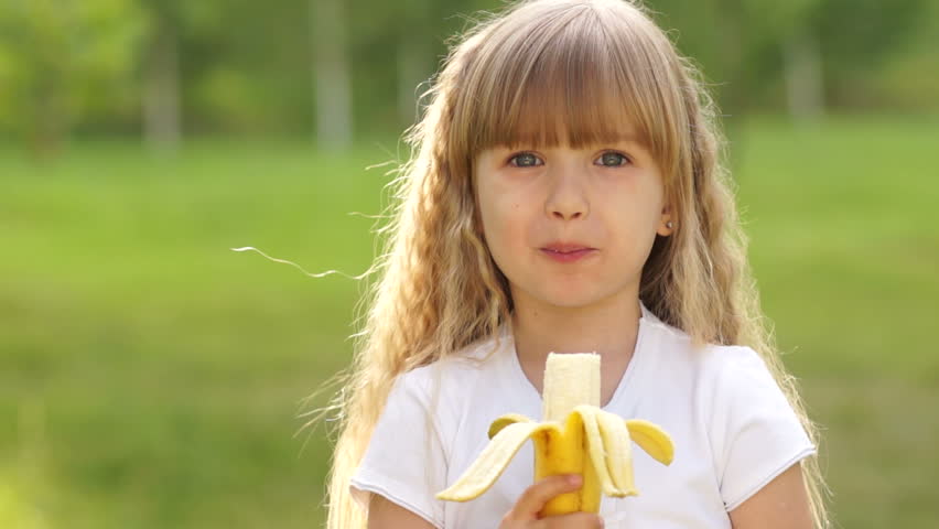 Girl eating a banana. Thumbs up. Ok
