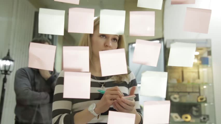 Creative businesswoman and man on brainstorming session in modern glass office. Uses different colour stickers Royalty-Free Stock Footage #24935321