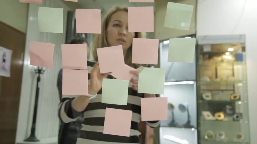 Creative businesswoman and man on brainstorming session in modern glass office. Uses different colour stickers Royalty-Free Stock Footage #24935327