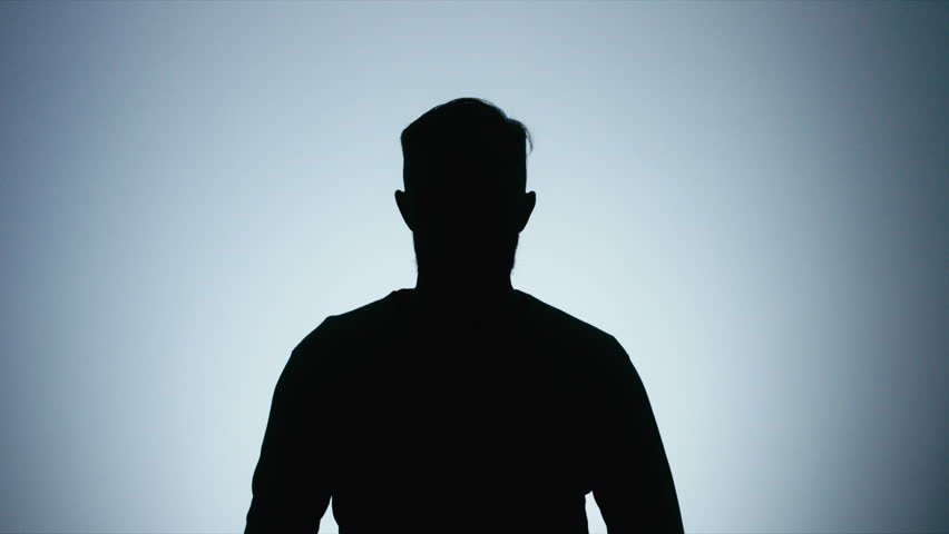 Half length silhouette portrait of bearded Caucasian male putting on headphones and listening to music on his phone against white background. 4K UHD 60 FPS slow motion