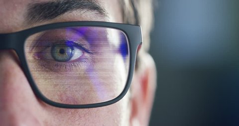 Close up of young businessman with blue eyes wearing the glasses looking on the waveform lines expressing concepts of stock market, augmented reality, technology, stock exchange  and finance