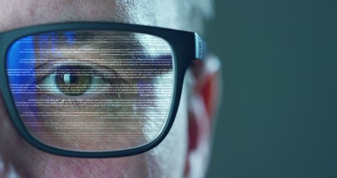Close up of young businessman with blue eyes wearing the glasses looking at waveform lines expressing concepts of stock market, augmented reality, technology, stock exchange  and finance