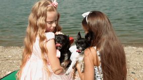 Two little girls with his chihuahua on the lake shore.  Rear View