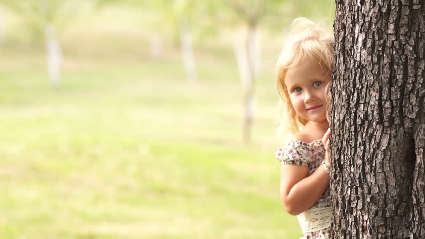 Little girl hiding behind a tree

