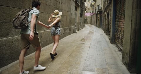 Young couple holding hands woman leading boyfriend walking down European street in Barcelona Spain POV travel concept