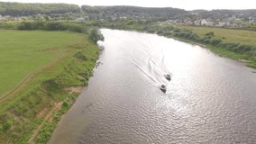 Video footage taken from bird's eye view by drone of floating speed boat on river in countryside. View from the top to the wide river,forest, large fields on sunny day. High speed boat video on river.