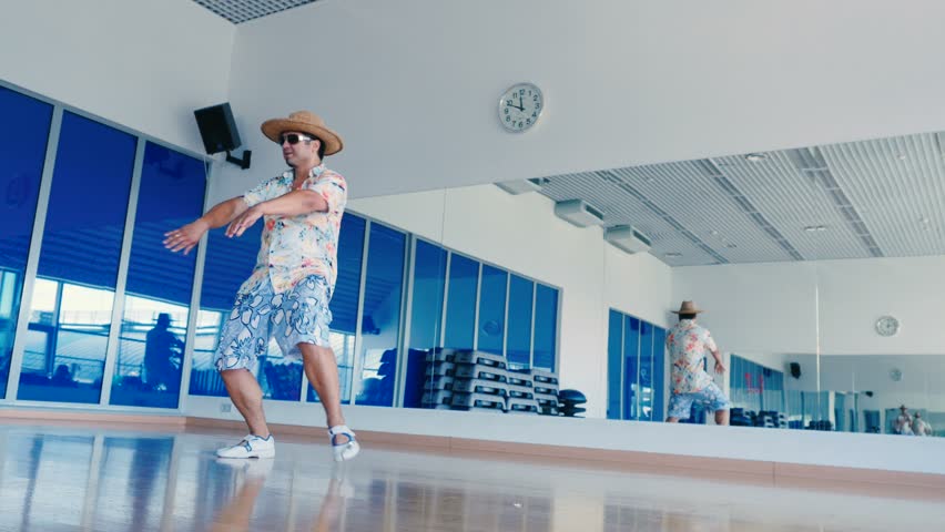 Man in hat and sunglasses dancing in front of mirror