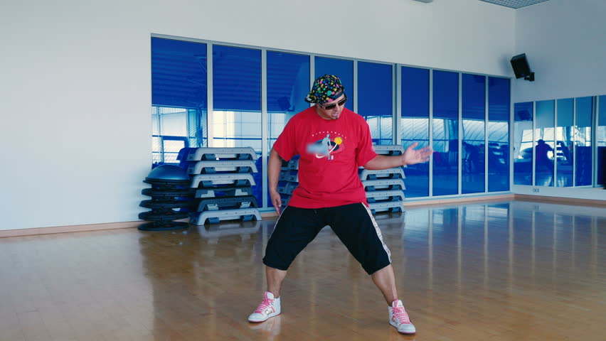 Happy man in cap and sunglasses dancing in the gym